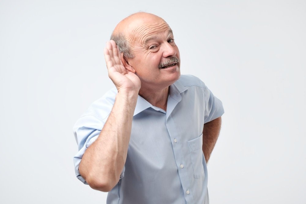Een oudere man die zijn hand bij zijn oor houdt